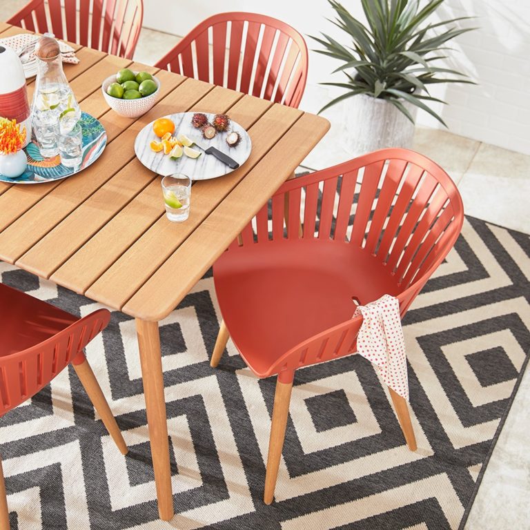 Overhead photo of wooden patio table and orange chairs. One orange chair has a rag draped over the arm.