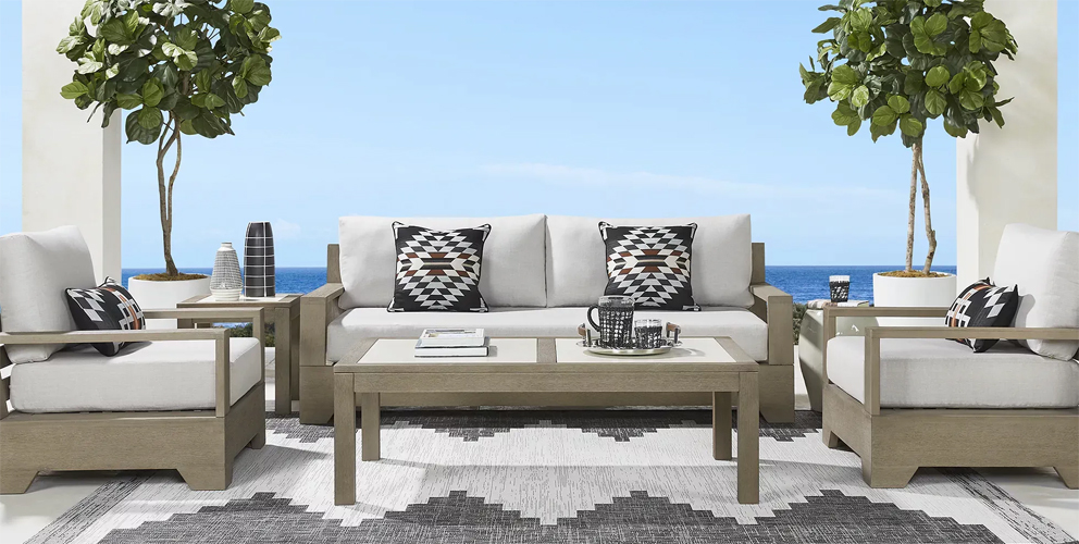 Photo of beige outdoor seating set with ivory cushions with an outdoor speaker on one of the tables