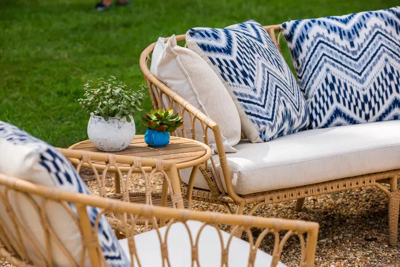 Photo of rattan table and outdoor seating set with ivory cushions and blue toss pillows