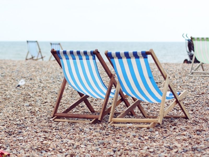 photo of two striped sling chairs on a beach